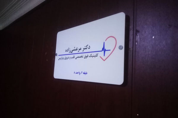 تابلوی راهنمای نام و تخصص پزشک نصب شده روی درب یا دیوار مطب.