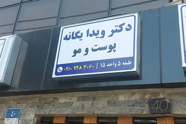تابلوی راهنمای مطب پزشک نصب شده روی سردر ورودی.